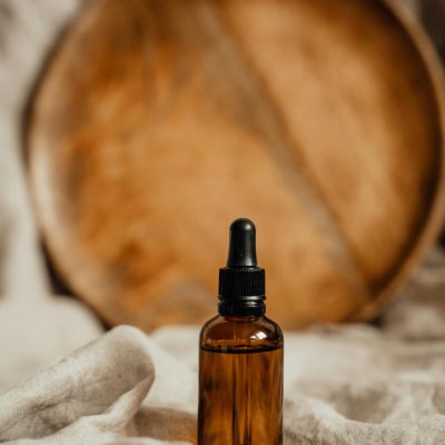 Amber glass dropper bottle with rustic wooden backdrop, ideal for skincare and cosmetics.